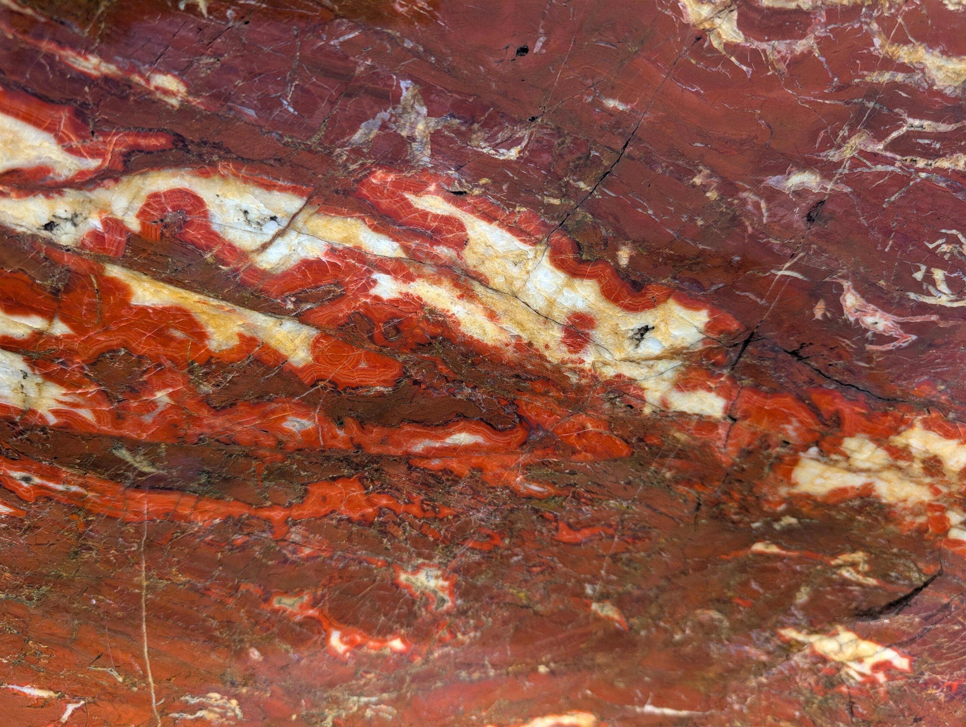 磨かれた紅加茂石の輝く表面をアップにし朱紅の深みを捉えた画像