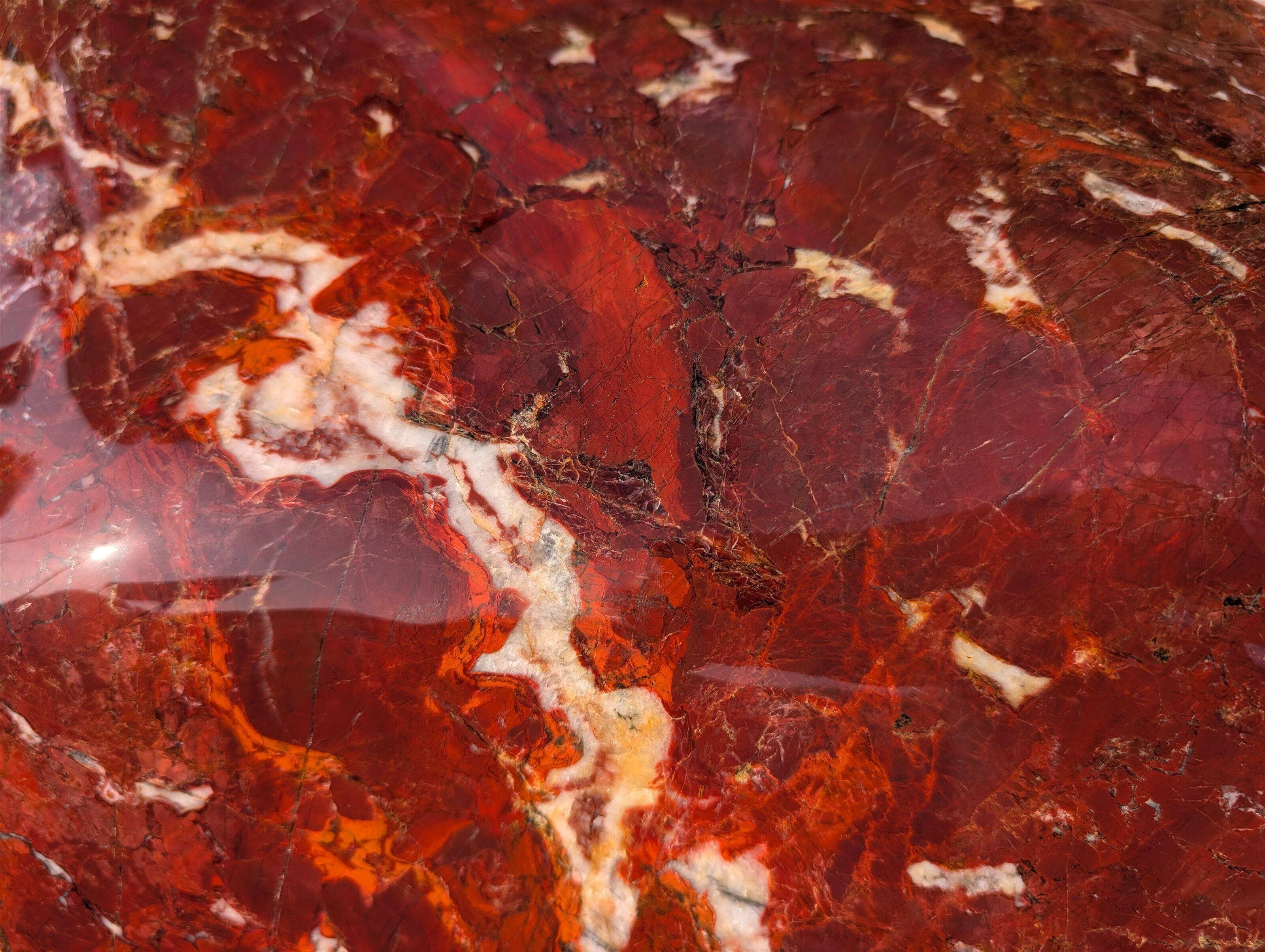 磨かれた紅加茂石の輝く表面をアップにし朱紅の深みを捉えた画像